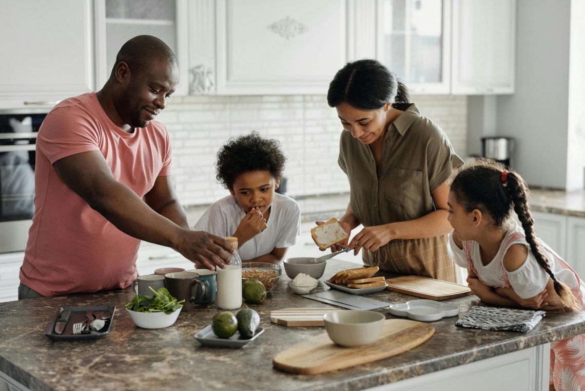 family of four making breakfast together in the kitchen