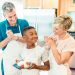 boy holding a plate of pancakes beside a couple in the kitchen